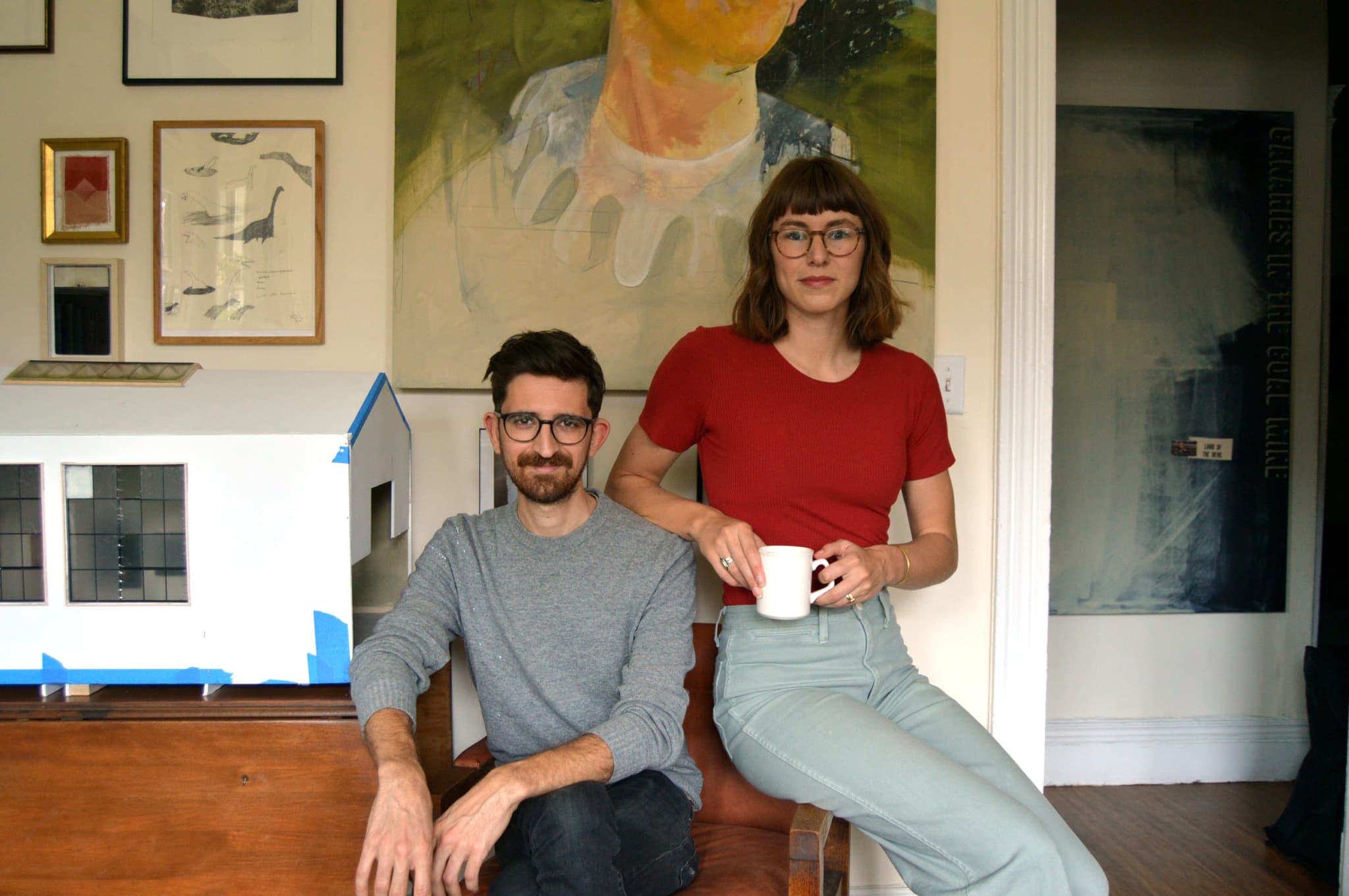 Eben Haines and Delaney Dameron are sitting beside the miniature Shelter in Place Gallery model.